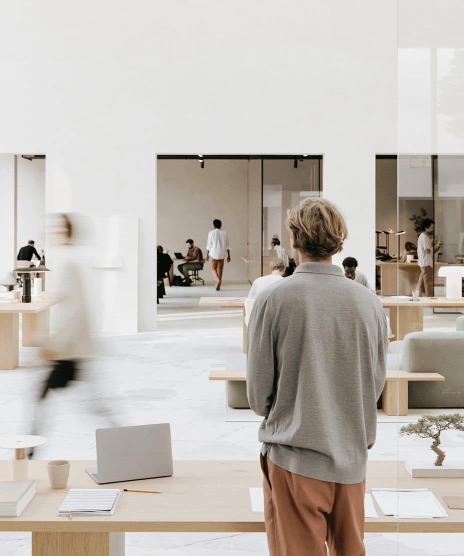 Un bureau moderne lumineux et ouvert où des personnes travaillent à des bureaux minimalistes en bois clair.