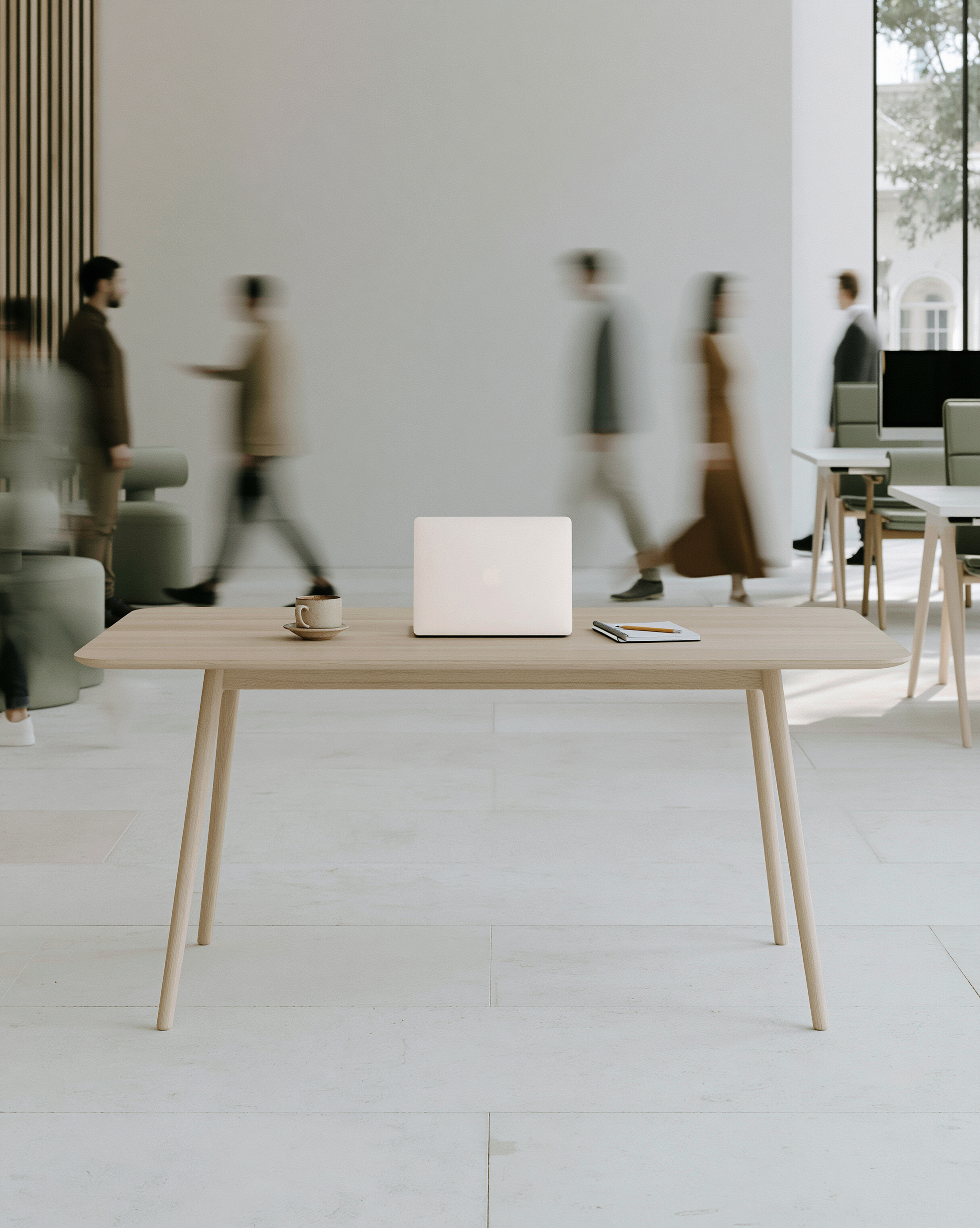 People moving through a calm modern office while one workstation sits ready